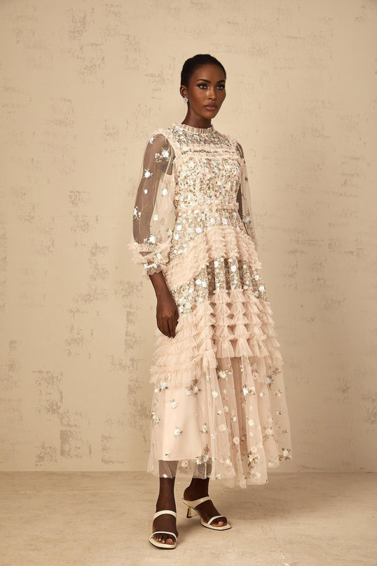 Woman wearing a long flowy maxi dress with floral embroidery and tiered tulle skirt in a romantic style