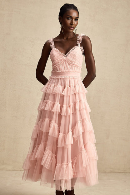 Woman wearing a long flowy maxi dress with layered ruffles and tulle fabric in a soft color