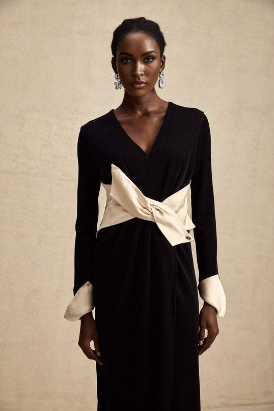 Woman wearing a long maxi dress with contrasting colors and a bowknot detail at the vneck