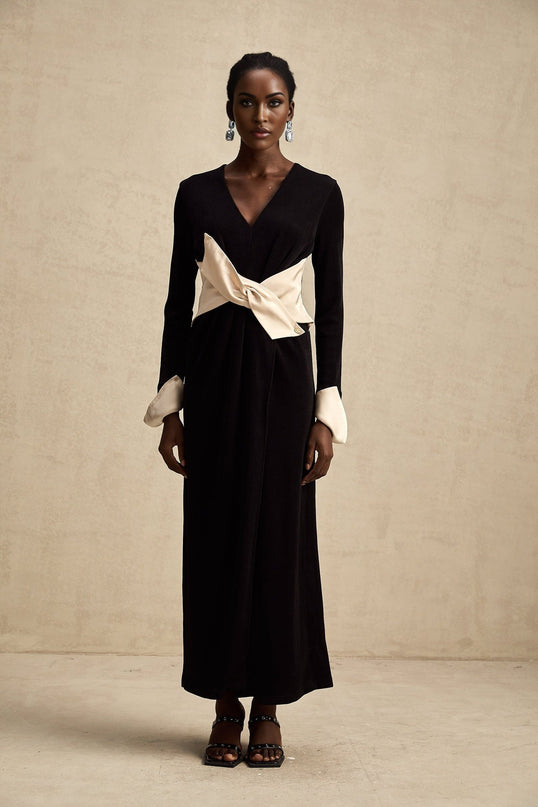 Woman wearing a long maxi dress with contrasting colors and a bowknot detail at the vneck