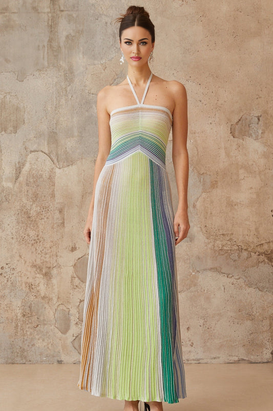 Woman wearing a long metallic knit backless maxi dress in a shimmering fabric standing in an elegant pose