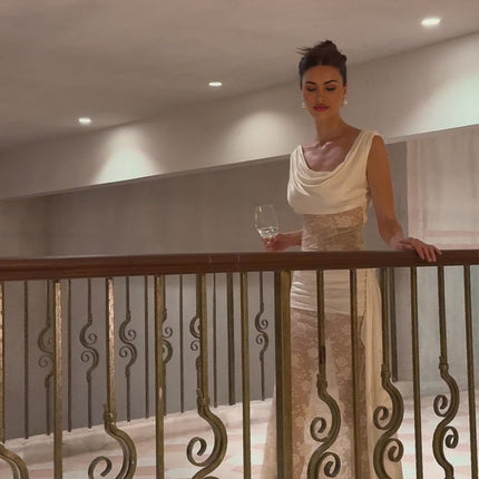 Woman wearing a long neutral colored maxi dress with floral lace panels and ribbon details