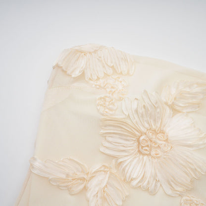 Woman wearing a long offshoulder maxi dress in neutral tones with embroidered details