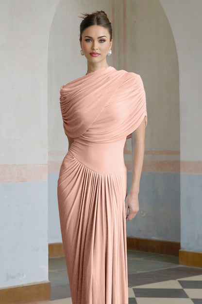 Woman wearing a long pink asymmetric pleated maxi dress with flowing fabric and a fitted waist
