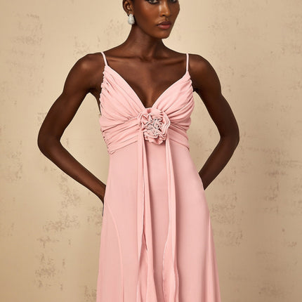 Woman wearing a long pink maxi dress with 3D floral petal details on tulle fabric flowing silhouette elegant formal gown