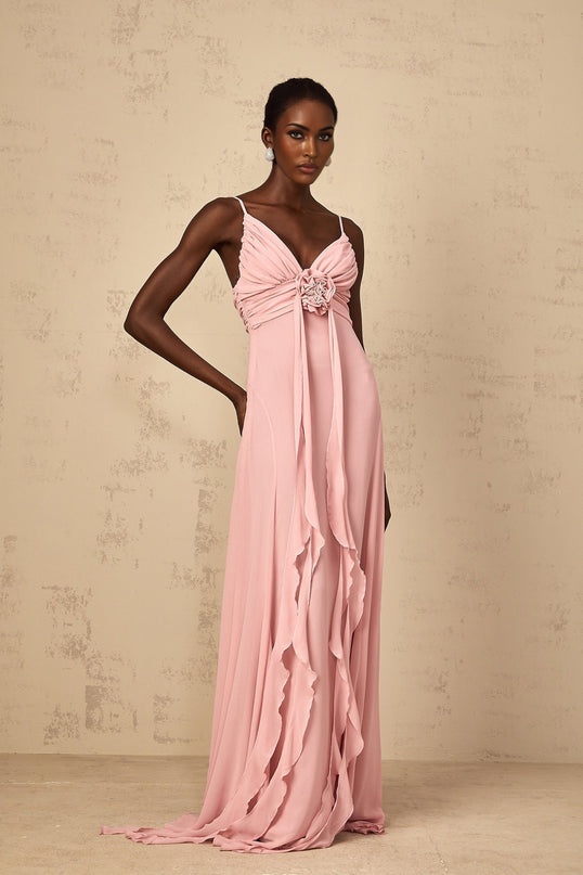 Woman wearing a long pink maxi dress with 3D floral petal details on tulle fabric flowing silhouette elegant formal gown