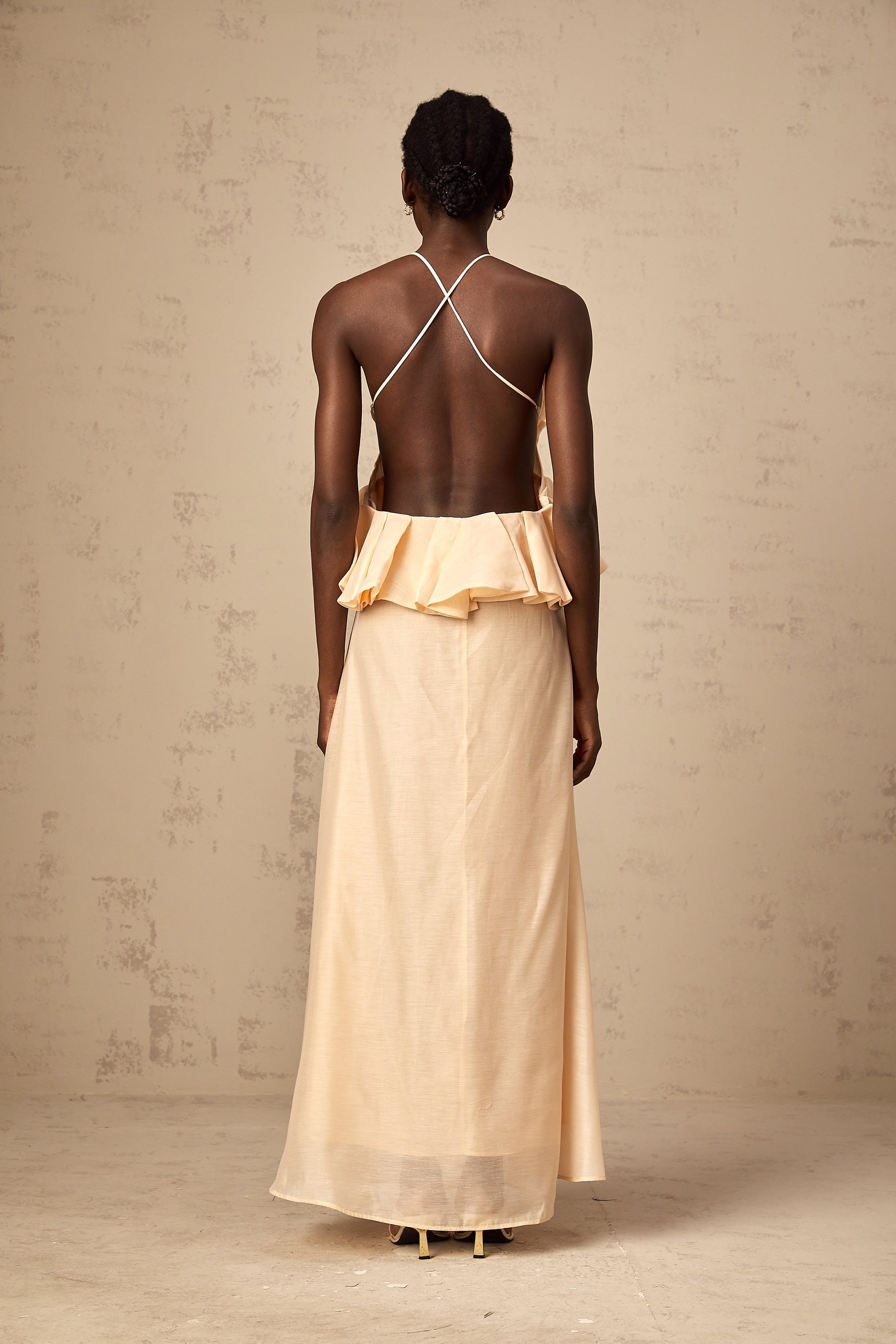 Woman wearing a long pink maxi dress with ruffled 3d petal details flowing from top to bottom
