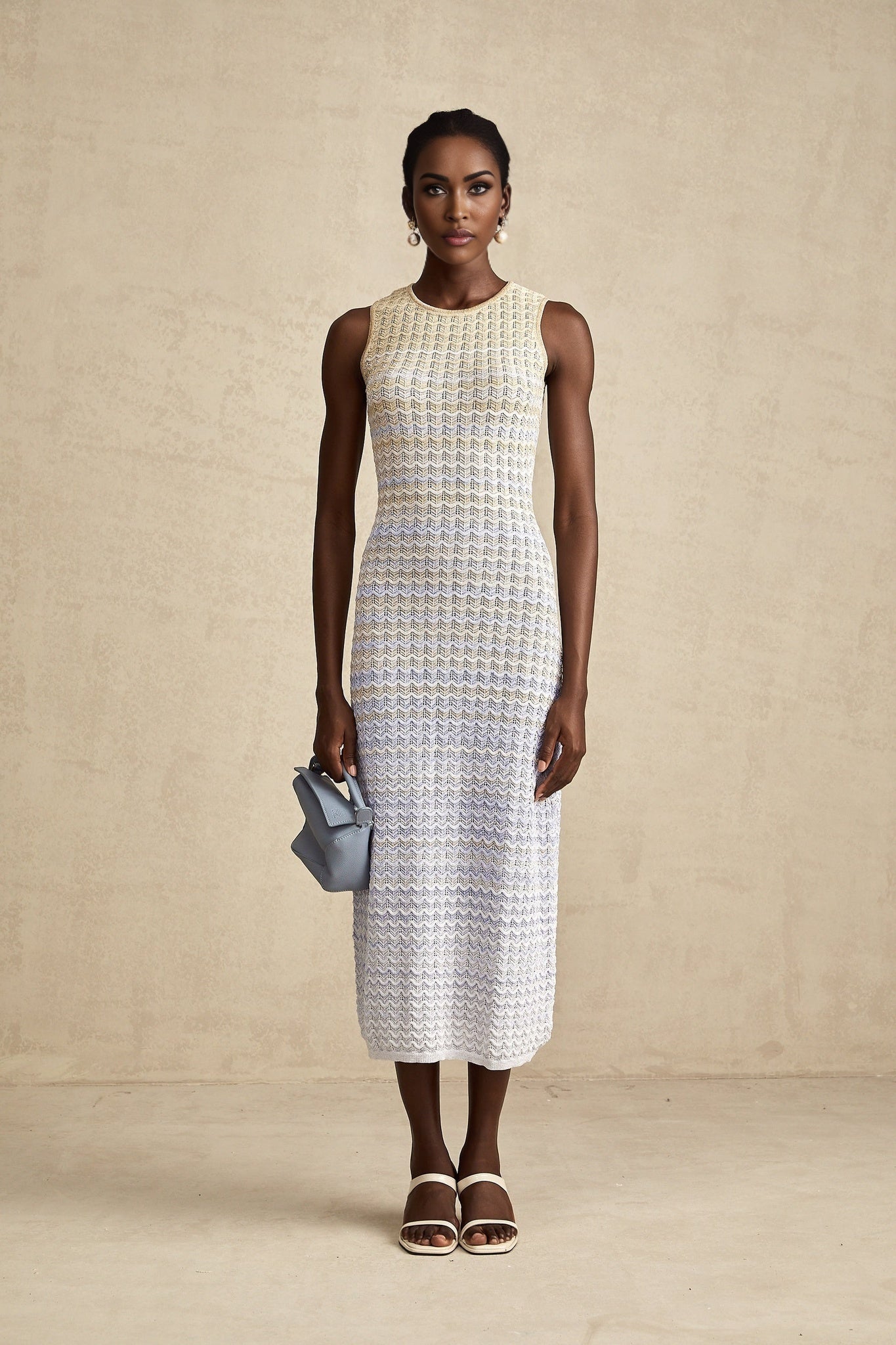 Woman wearing a long ribbed knit dress with contrasting color details and a midi length