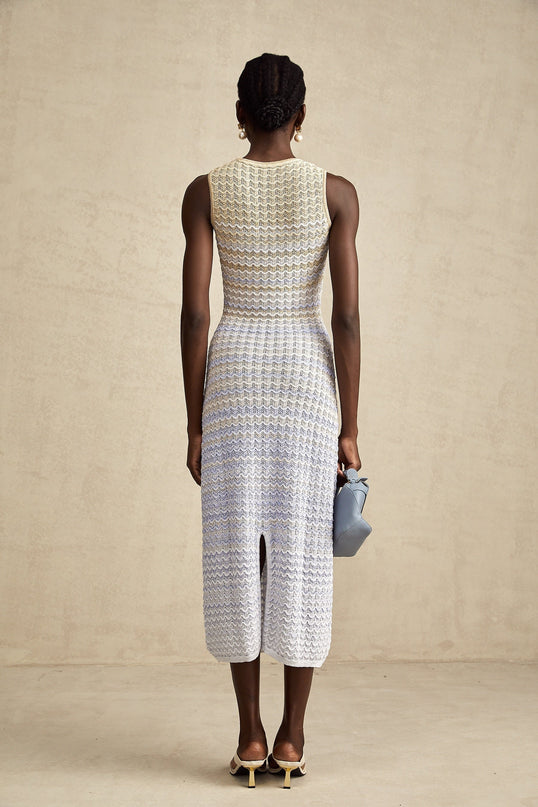 Woman wearing a long ribbed knit dress with contrasting color details and midi length