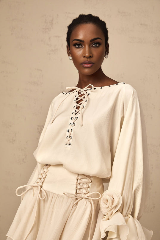 Woman wearing a matching blouse and skirt set in light fabric with ruffles and self tie details