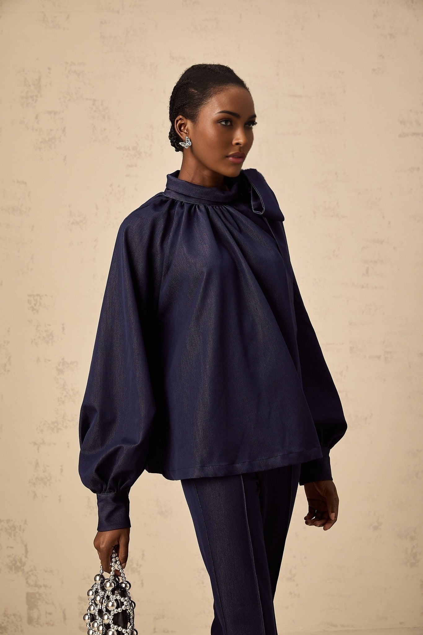 Woman wearing a matching denim blue outfit consisting of a flared blouse and trousers called Mathilde