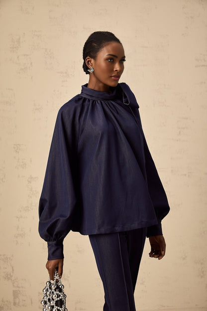 Woman wearing a matching denim blue outfit consisting of a flared blouse and trousers called Mathilde