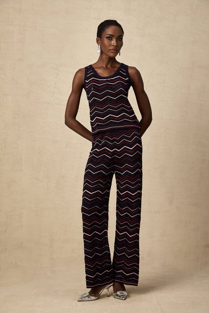 Woman wearing a matching set consisting of a crochet knit top and trousers with a zigzag pattern in a light color