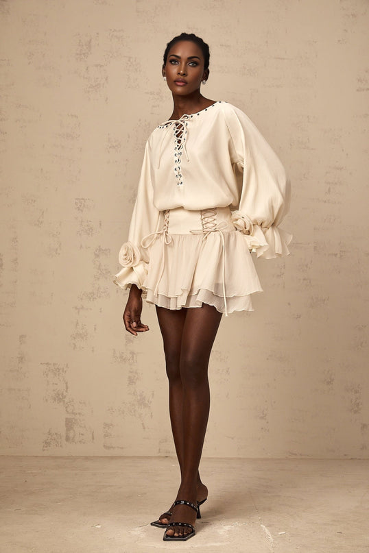 Woman wearing a matching set consisting of a ruffled blouse with selftie details and a coordinating skirt in a light fabric