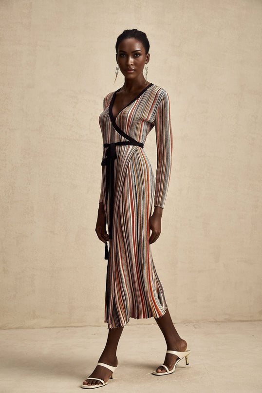 Woman wearing a metallic striped midi dress with wrap design and long sleeves