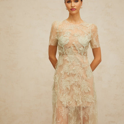 Woman wearing a mintgreen midi dress with floral lace pattern standing in a relaxed pose