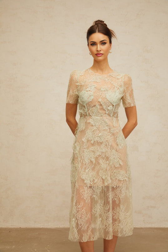Woman wearing a mintgreen midi dress with floral lace pattern standing in a relaxed pose