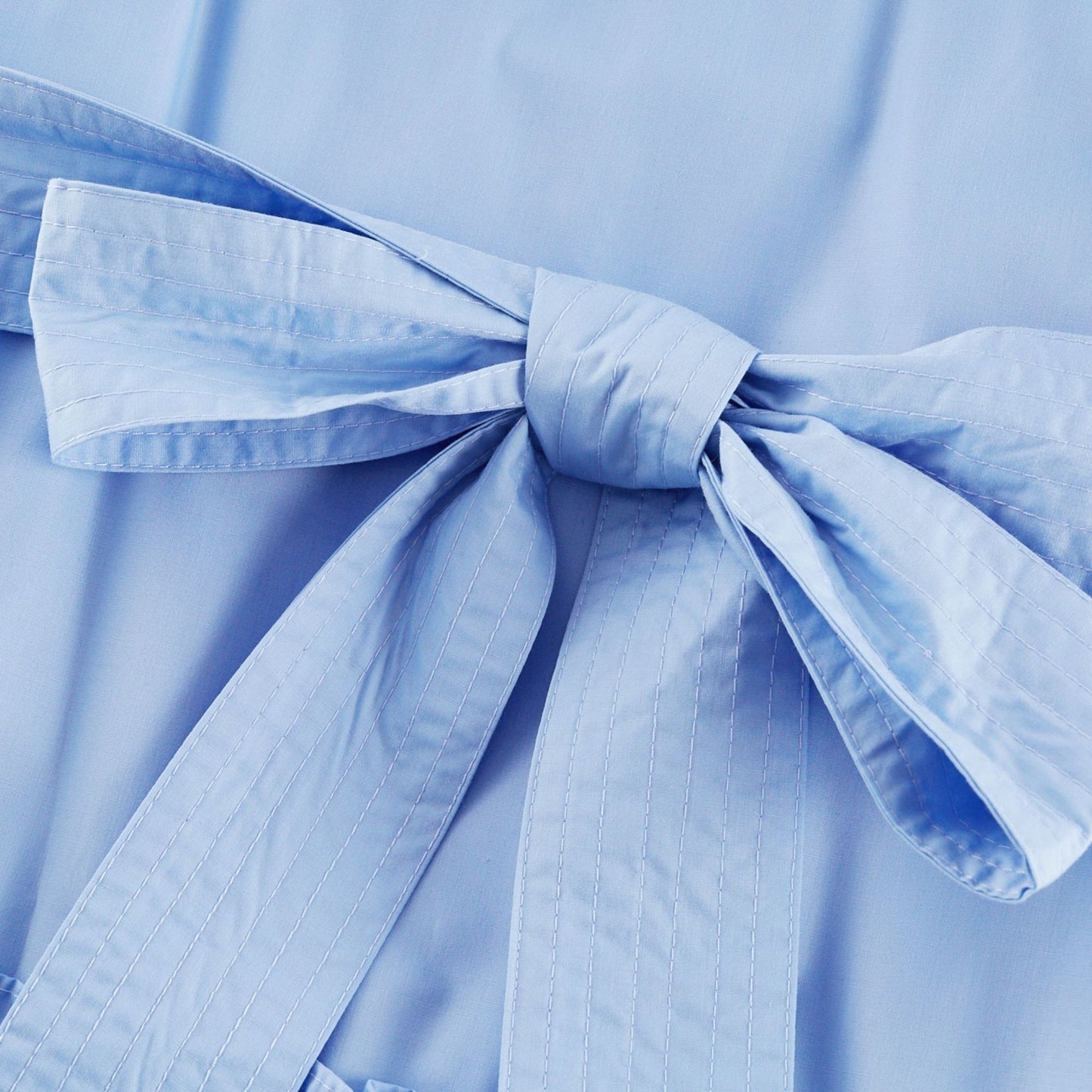 Woman wearing a navy blue offshoulder tiered midi dress with ruffle details and flowing skirt standing against a plain background