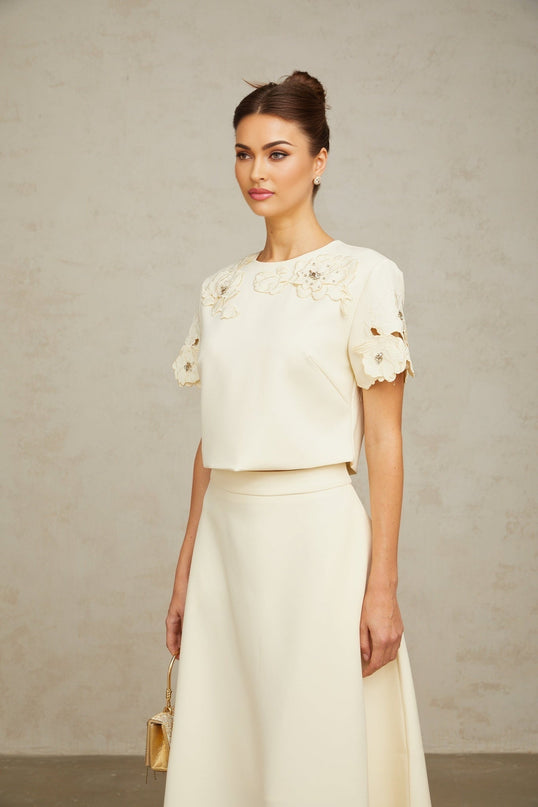 Woman wearing a neutral colored matching set with a 3D petal textured top and skirt named Coralie