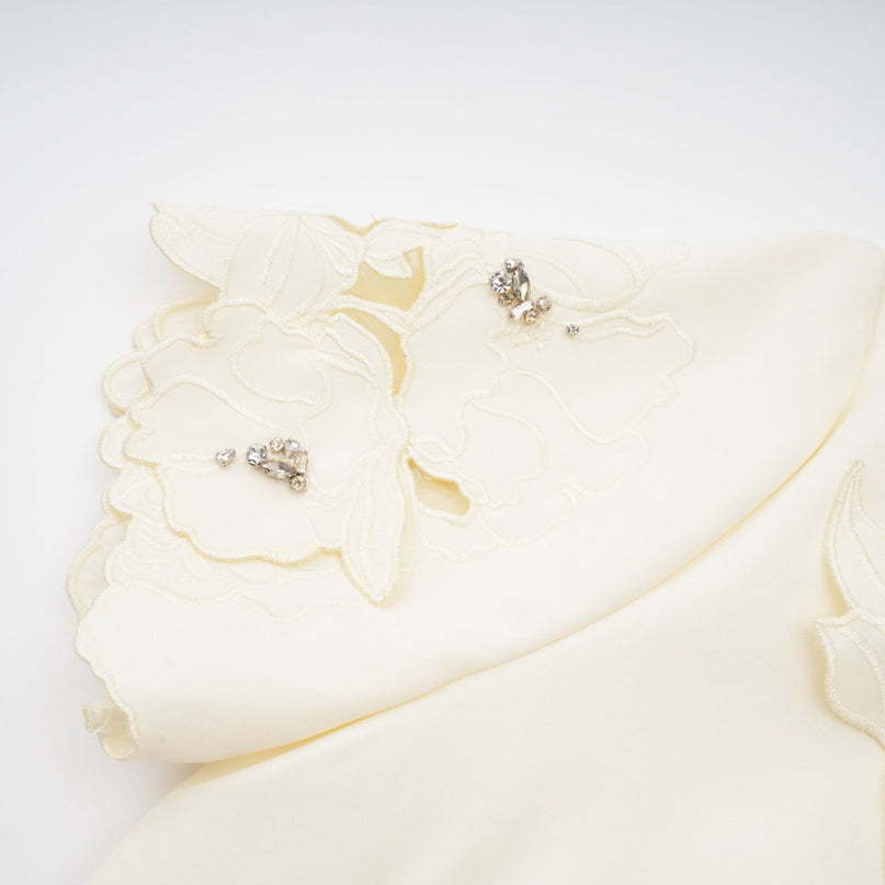 Woman wearing a neutral colored matching set with a top and skirt featuring threedimensional petal details