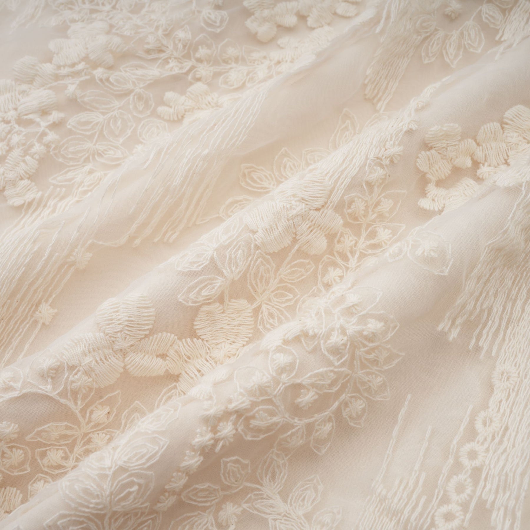 Woman wearing a neutral colored midi dress with lace embroidery details and short sleeves