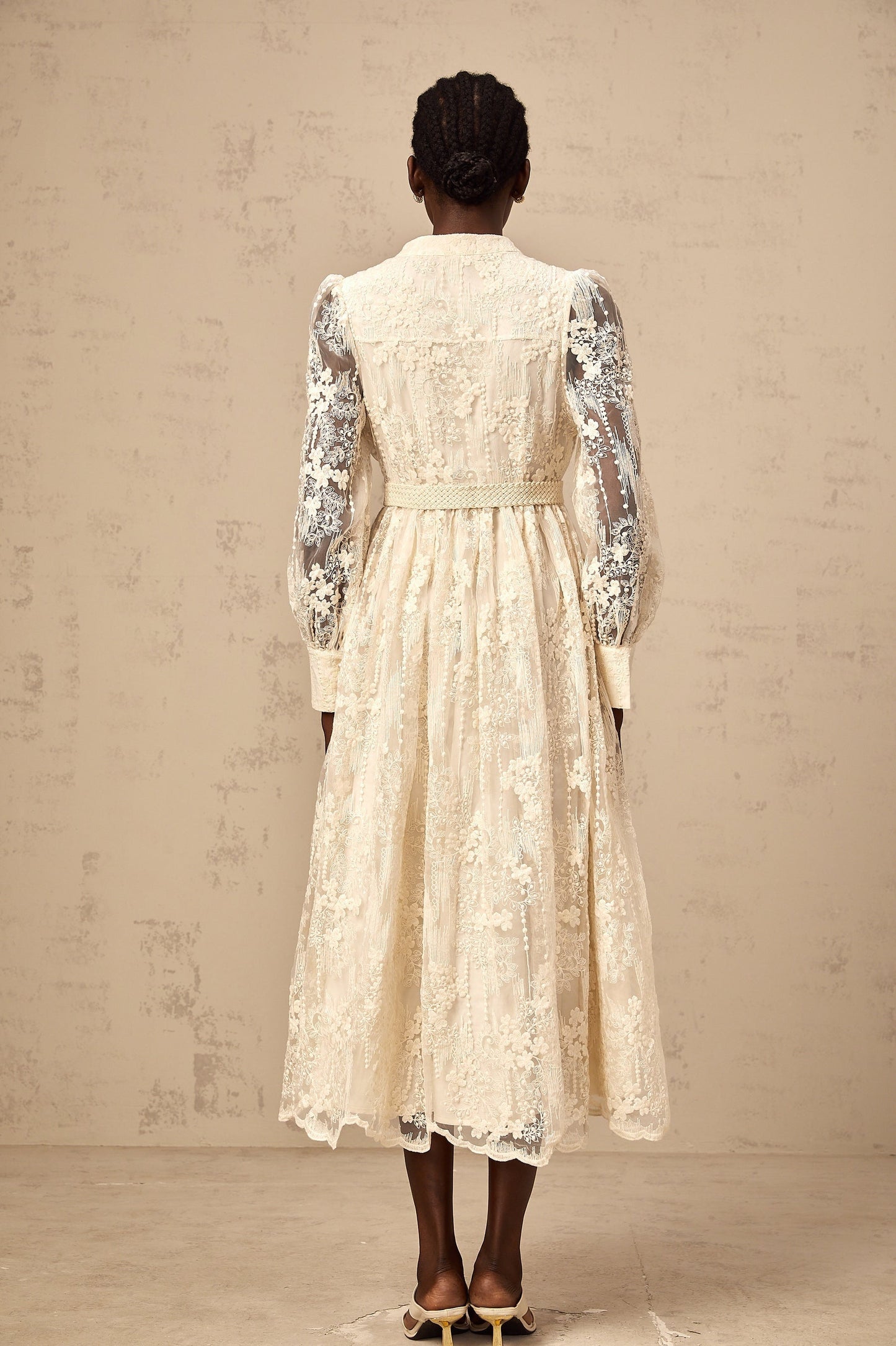 Woman wearing a neutral colored midi dress with lace embroidery details standing in a casual pose