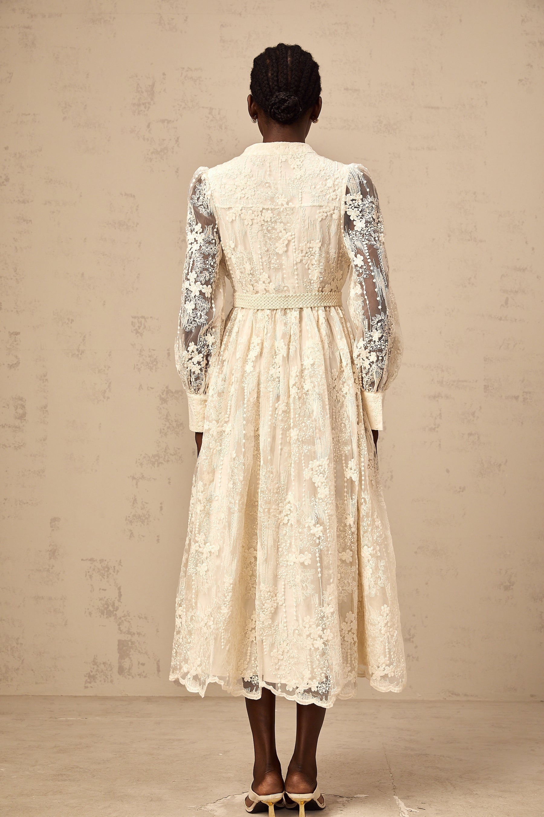 Woman wearing a neutral colored midi dress with lace embroidery details standing in a casual pose
