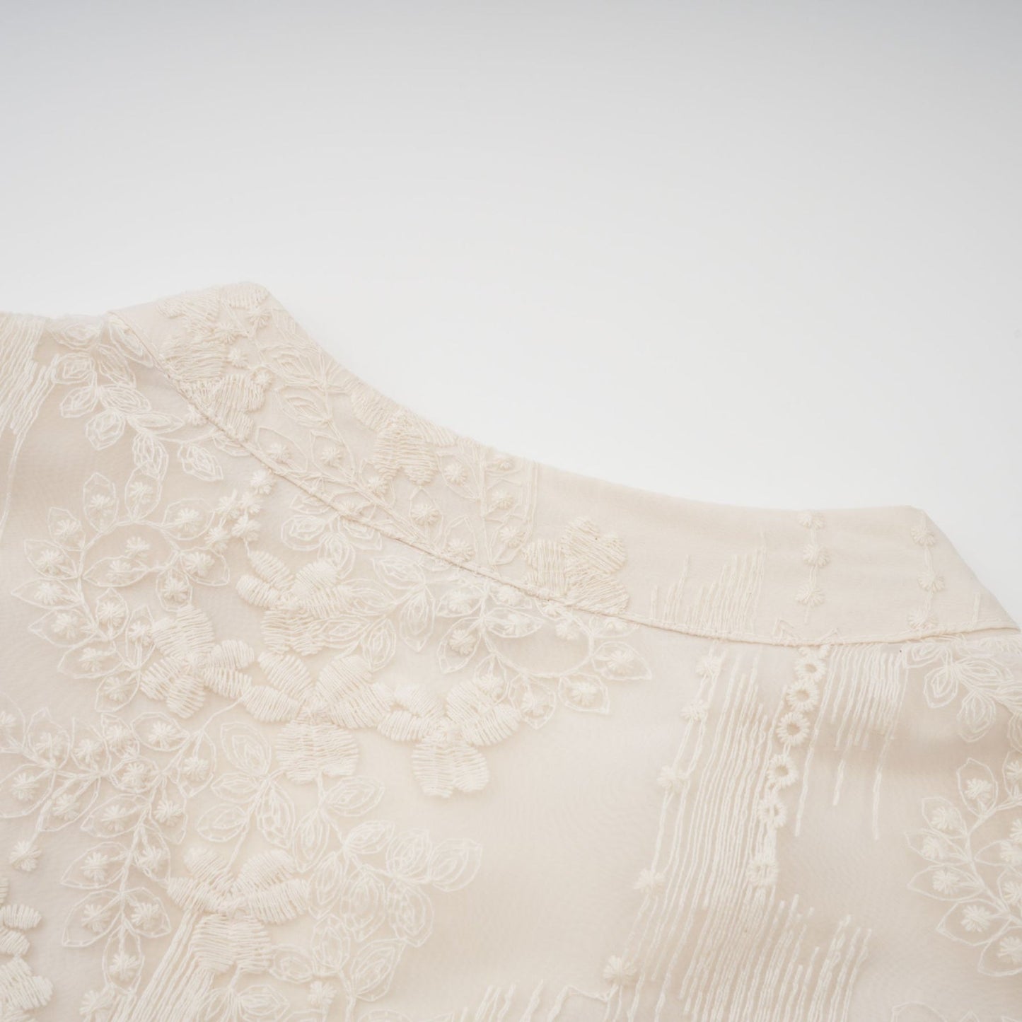 Woman wearing a neutral colored midi dress with lace embroidery details standing in a relaxed pose