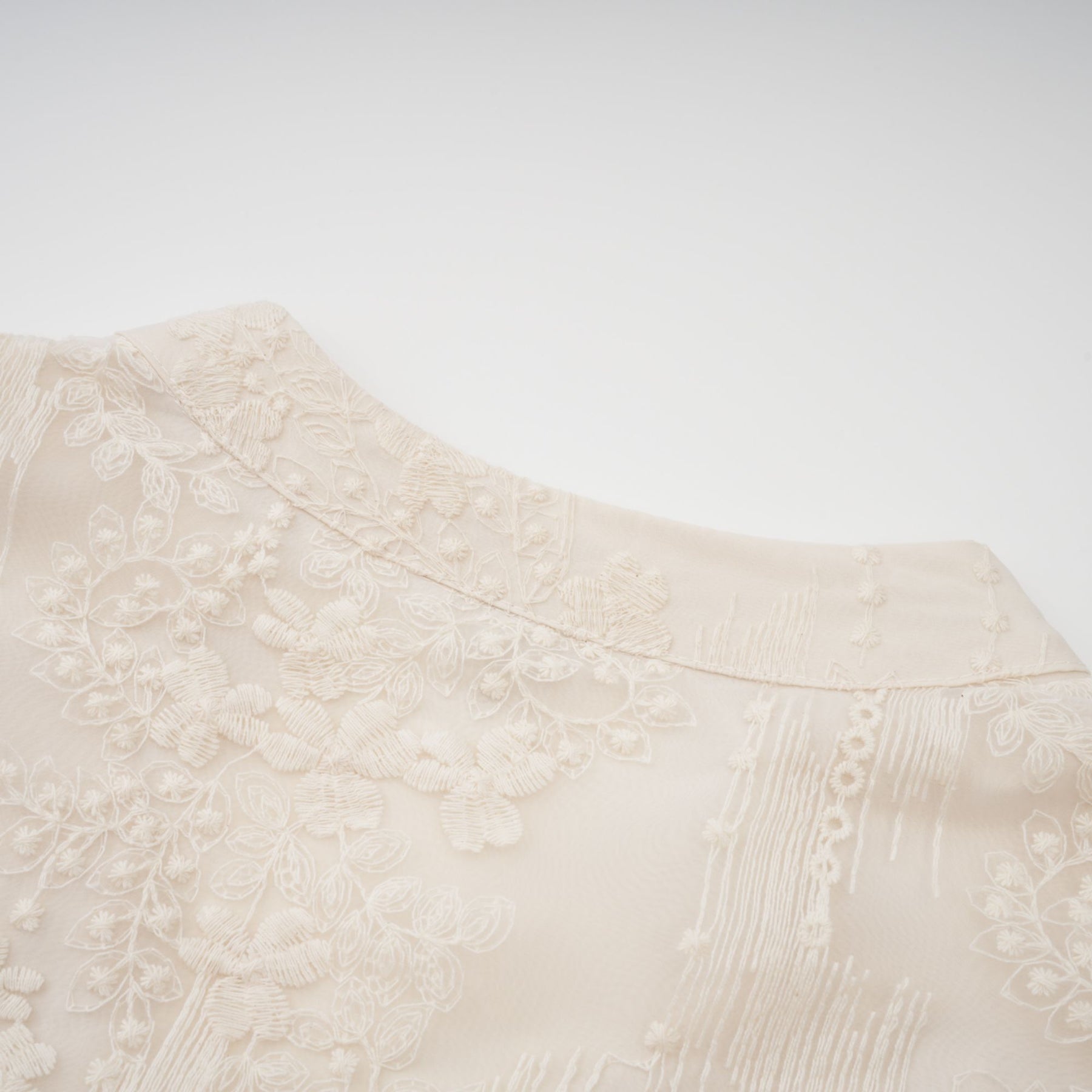 Woman wearing a neutral colored midi dress with lace embroidery details standing in a relaxed pose