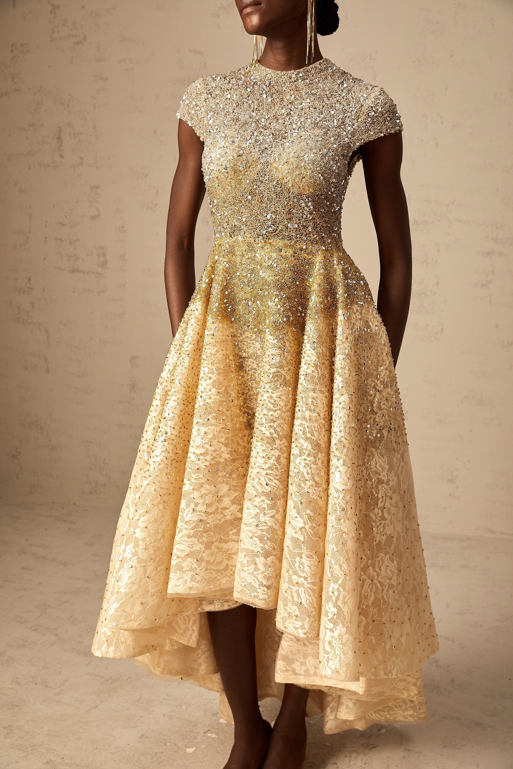 Woman wearing a neutral colored sequined dress with high low hemline