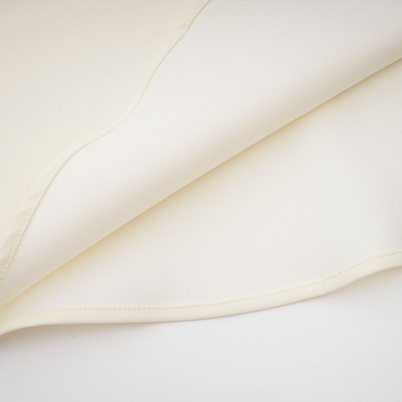 Woman wearing a neutralcolored matching set consisting of a top and skirt with threedimensional petal details