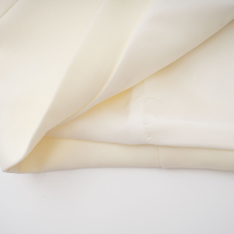 Woman wearing a neutralcolored matching set with a top and skirt featuring 3D petal details on a plain background