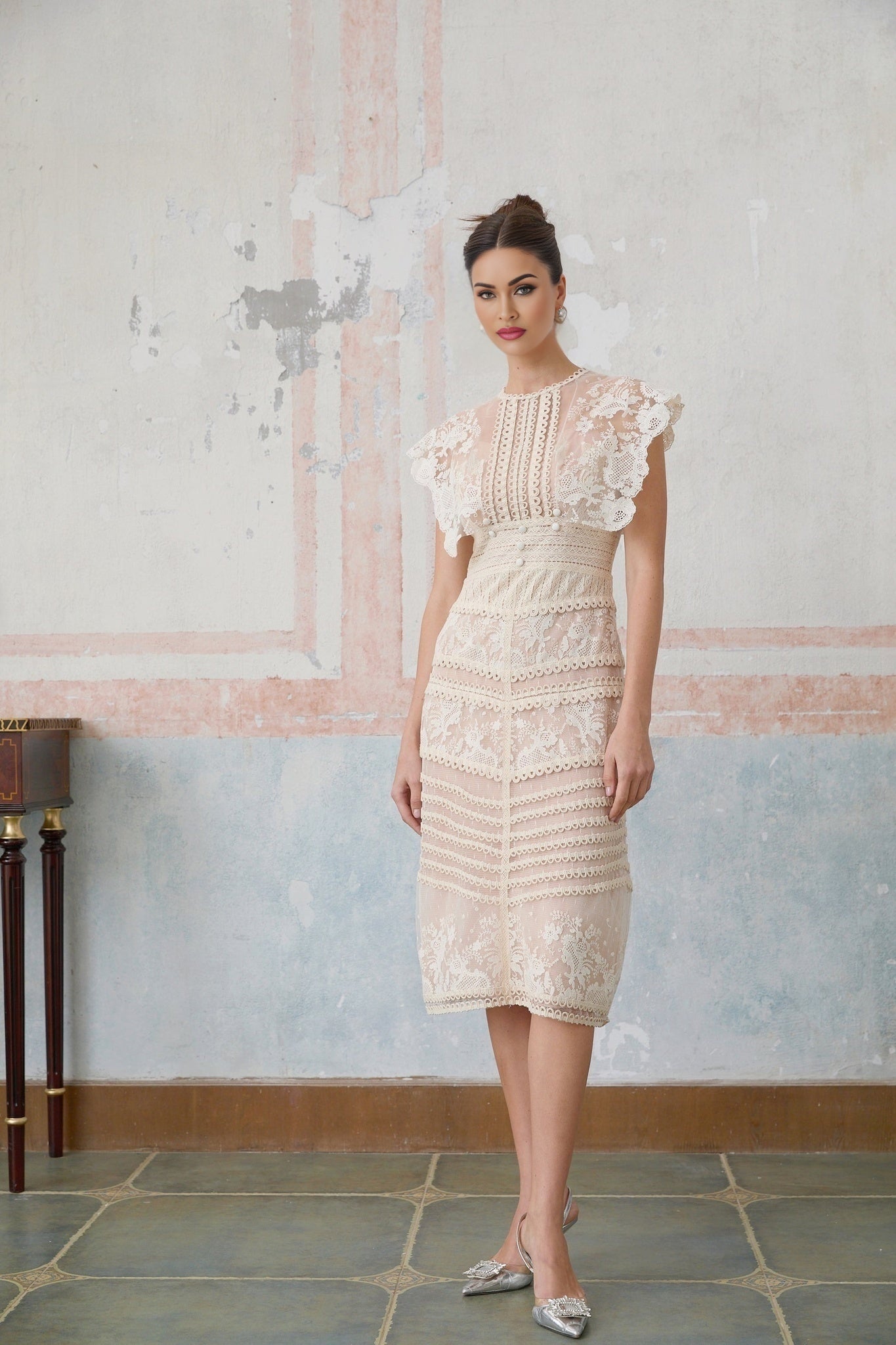 Woman wearing a neutralcolored midi dress with floral embroidery and lace details standing in a casual pose