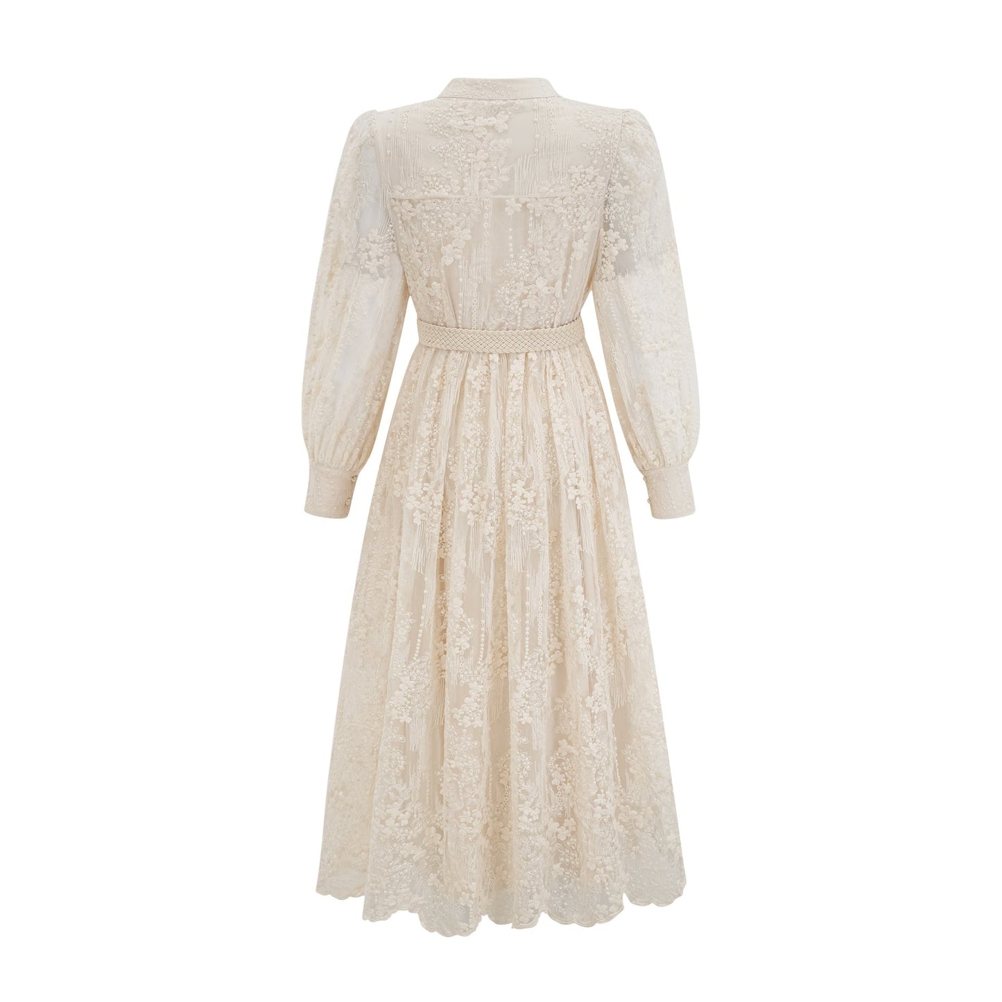 Woman wearing a neutralcolored midi dress with lace embroidery details standing in a relaxed pose