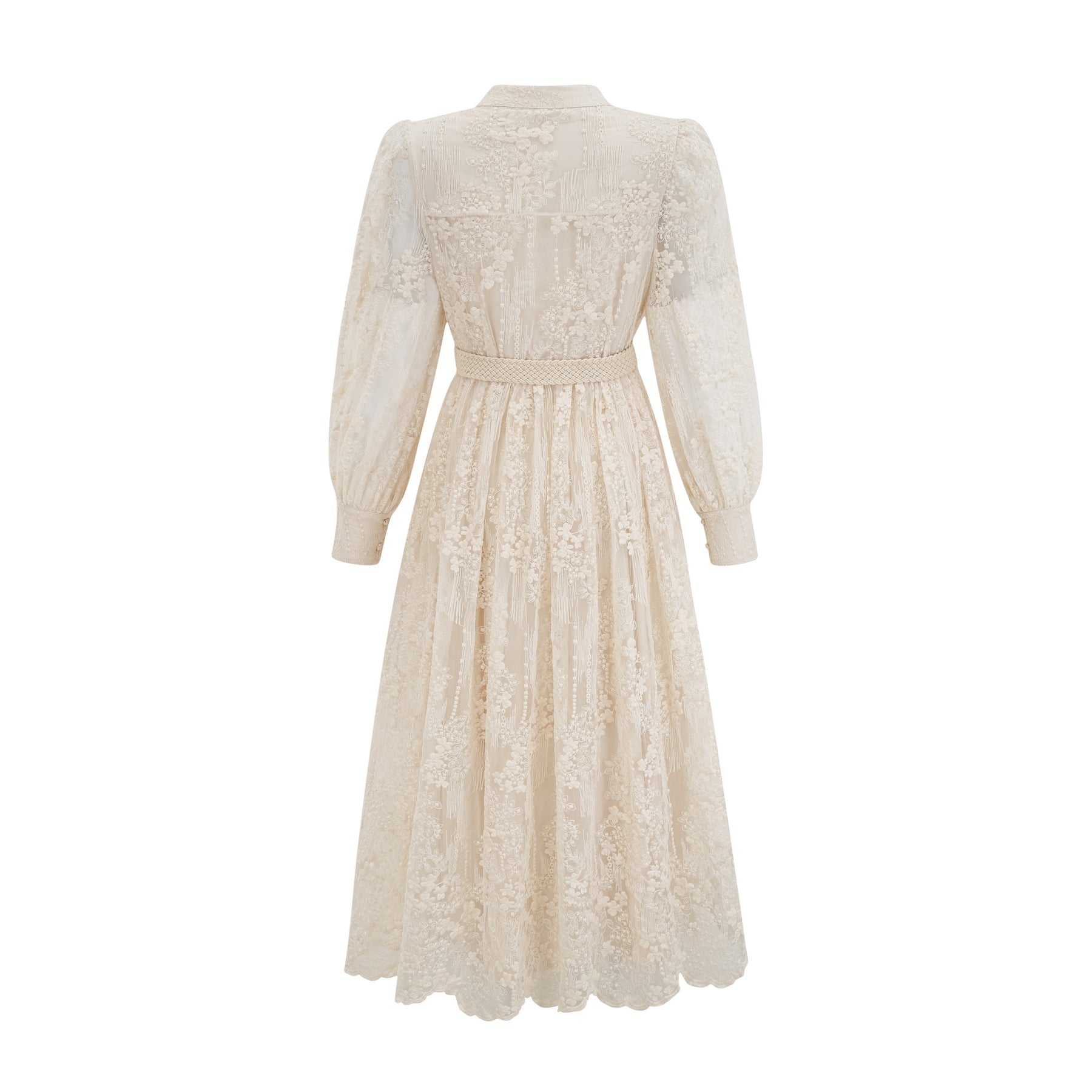 Woman wearing a neutralcolored midi dress with lace embroidery details standing in a relaxed pose