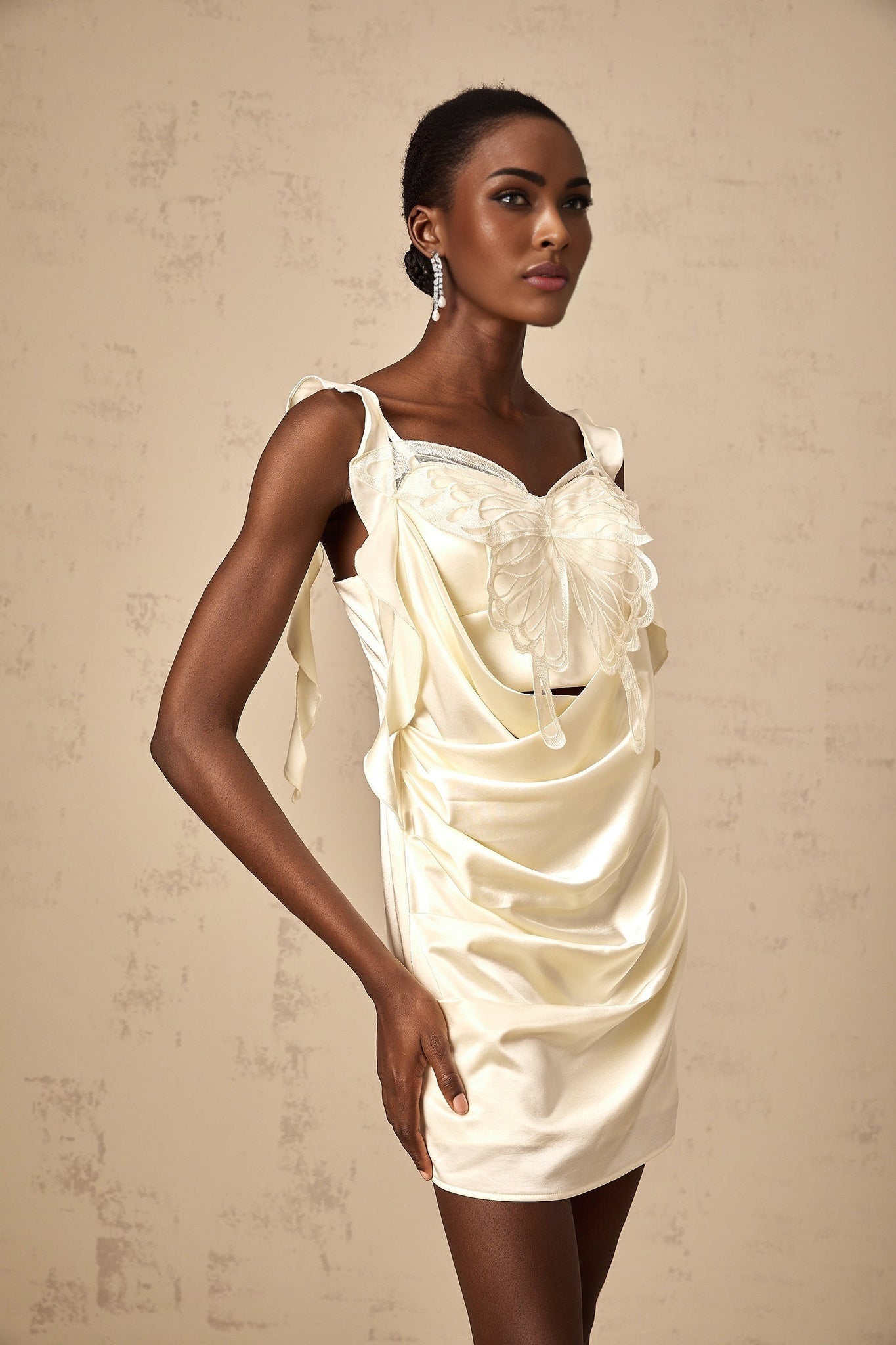 Woman wearing a neutralcolored mini dress with butterfly print and draped design