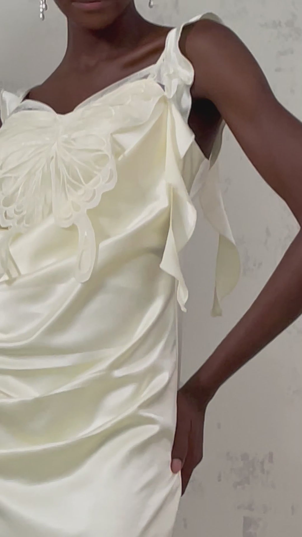 Woman wearing a neutralcolored mini dress with butterfly print and draped design