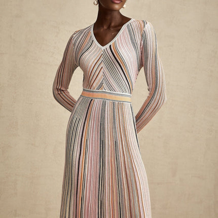 Woman wearing a pink metallic pleated midi dress with a flowy skirt and fitted bodice standing in a neutral background