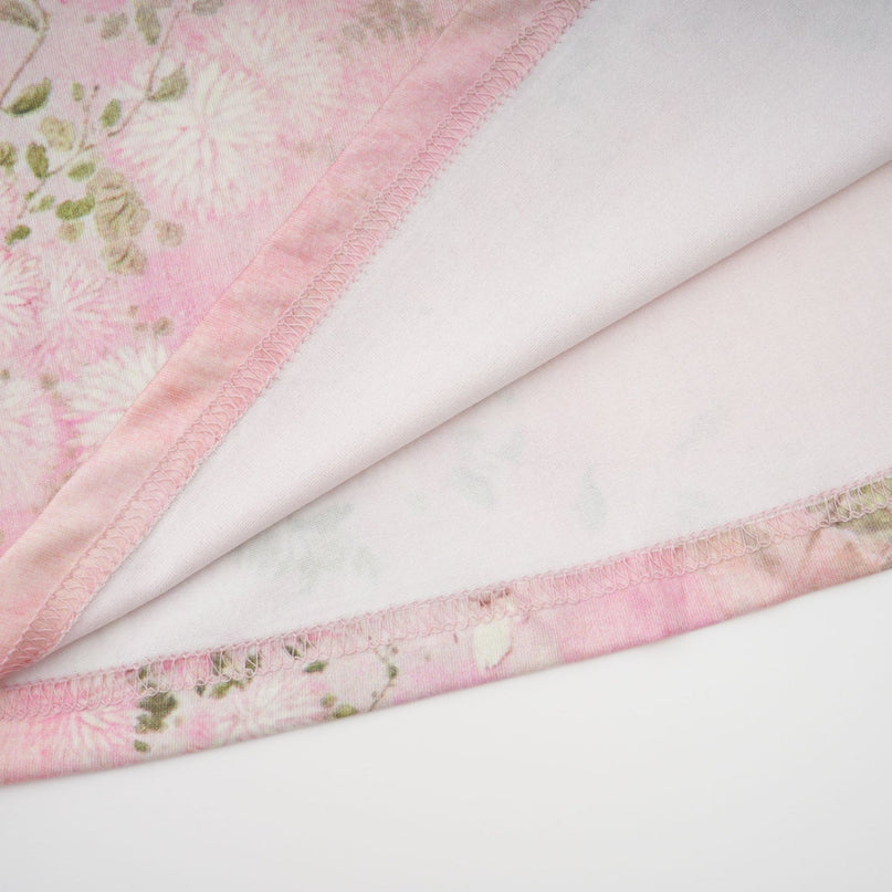 Woman wearing a pink midi dress with floral print and embellishments standing in a neutral background