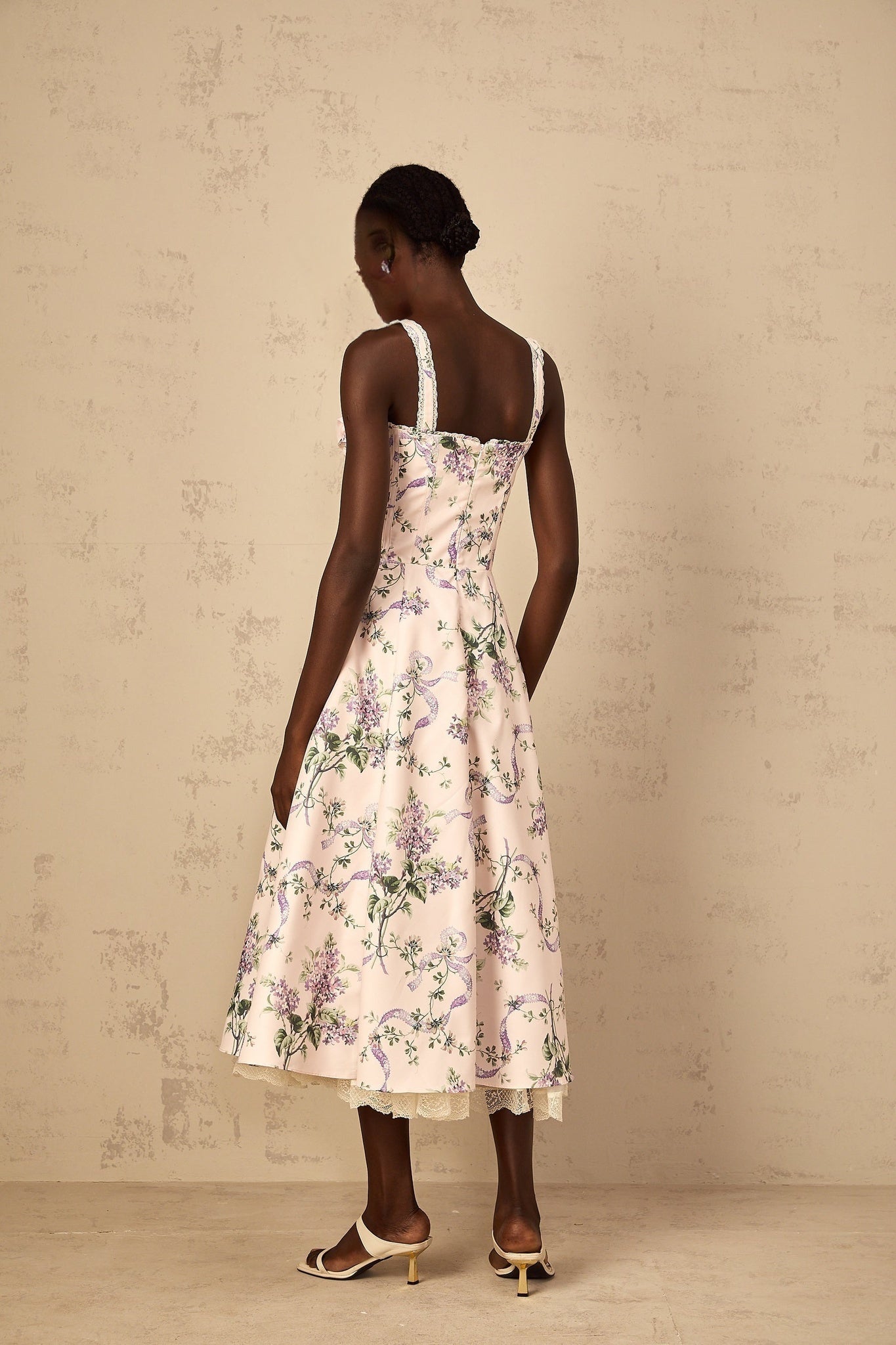 Woman wearing a pink midi dress with floral print and shirred detailing