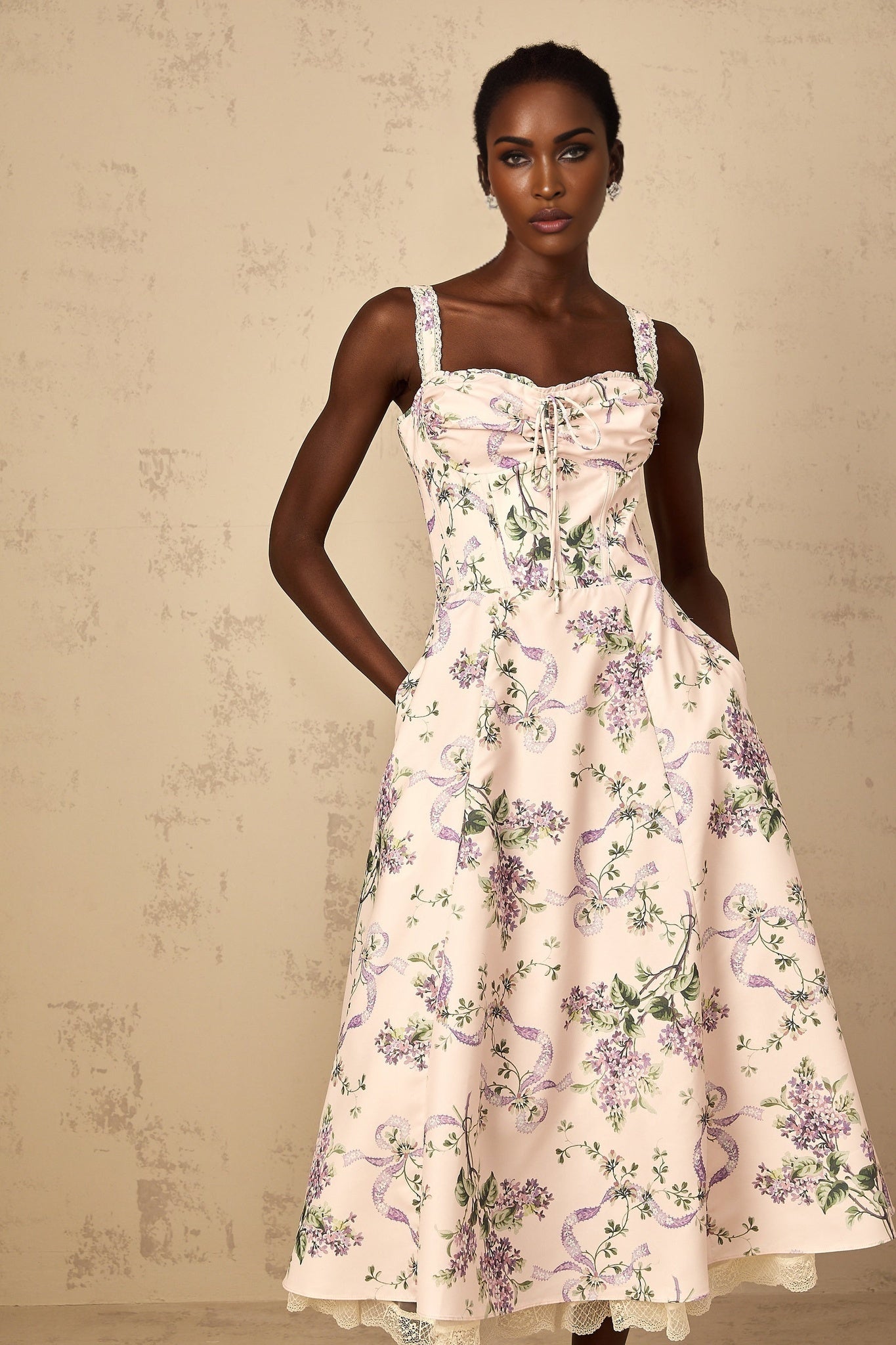 Woman wearing a pink midi dress with floral print and shirred details