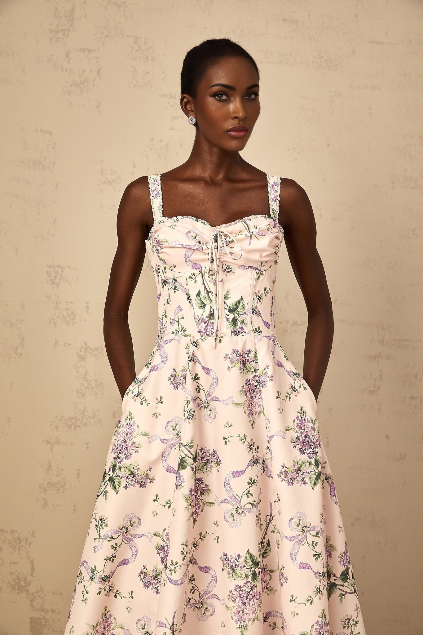 Woman wearing a pink midi dress with floral print and shirred details