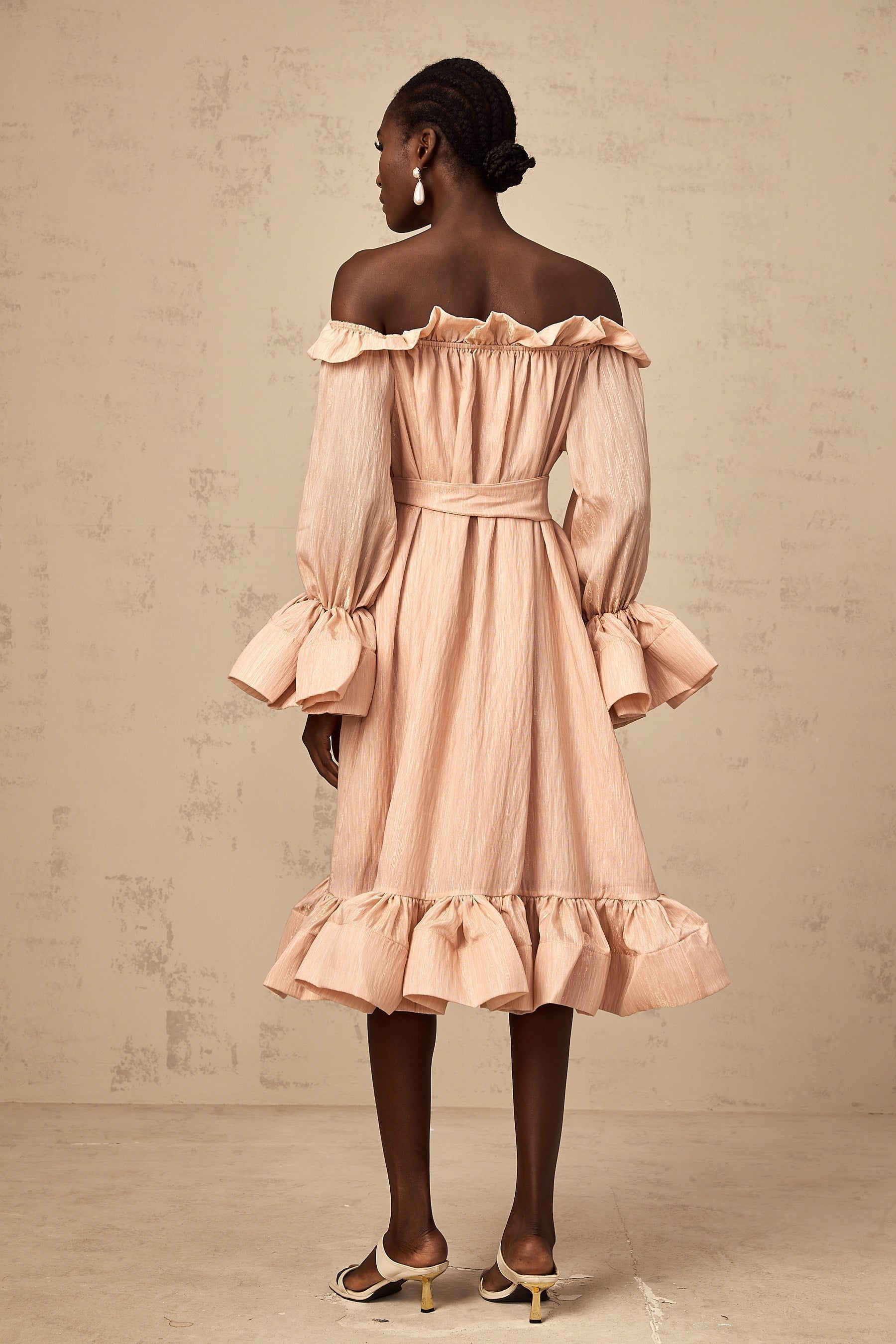 Woman wearing a pink midi dress with ruffled details and tied waist