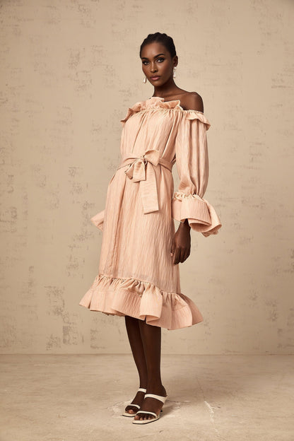 Woman wearing a pink midi dress with tied waist and ruffled details