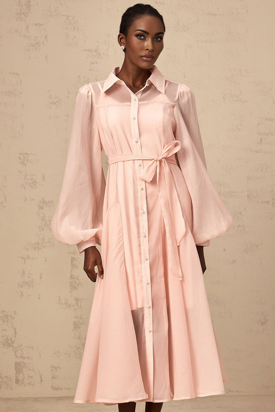 Woman wearing a pink midi length shirt dress with a tied waist detail
