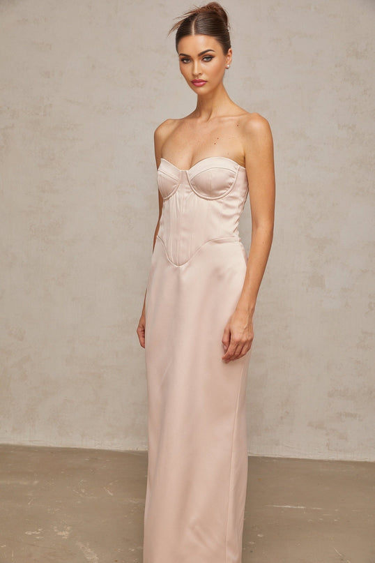 Woman wearing a pink off shoulder corset style satin maxi dress with a fitted bodice and flowing skirt