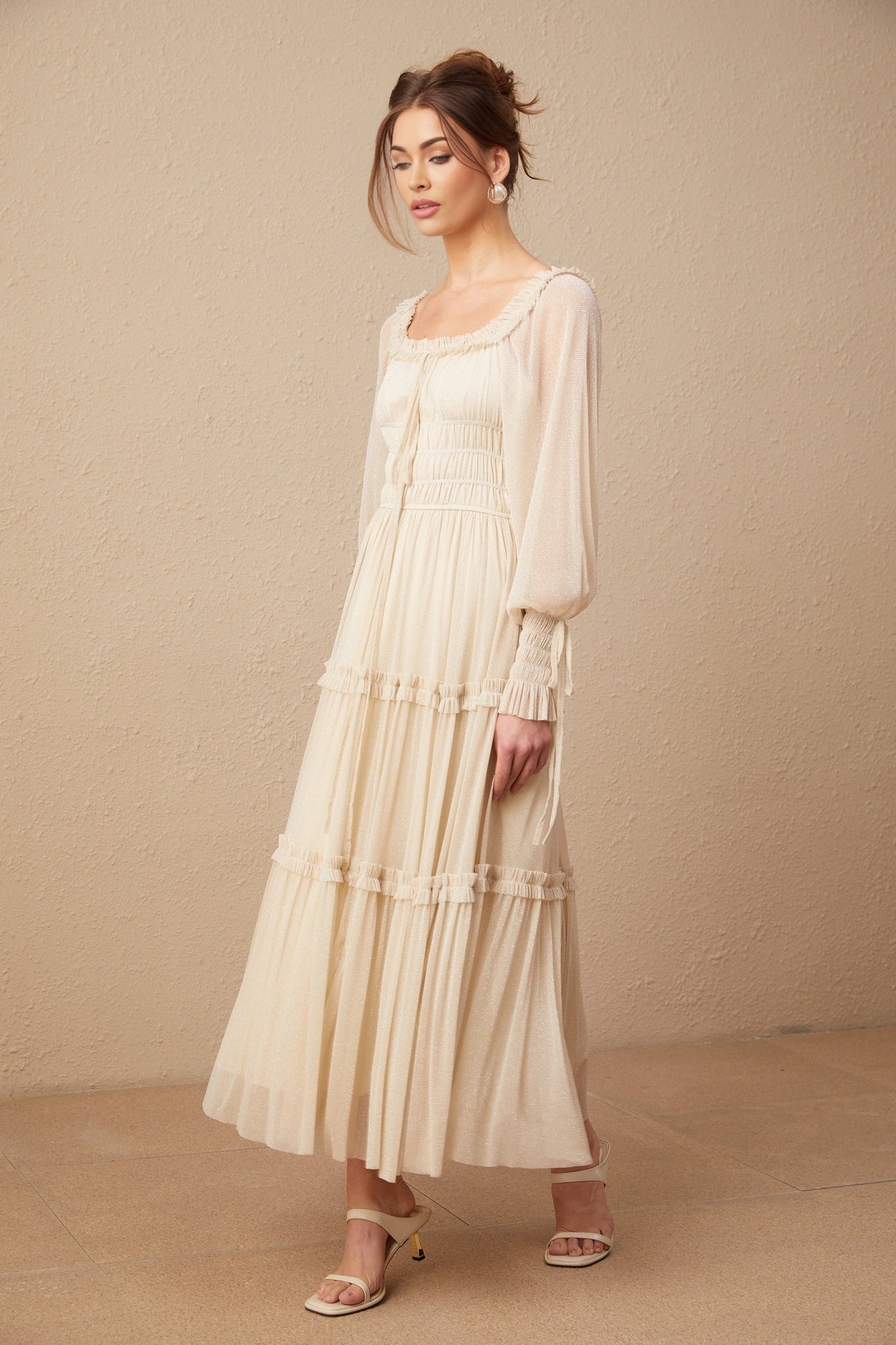 Woman wearing a pleated metallic midi dress with shirred detailing and a flowy silhouette named Camille