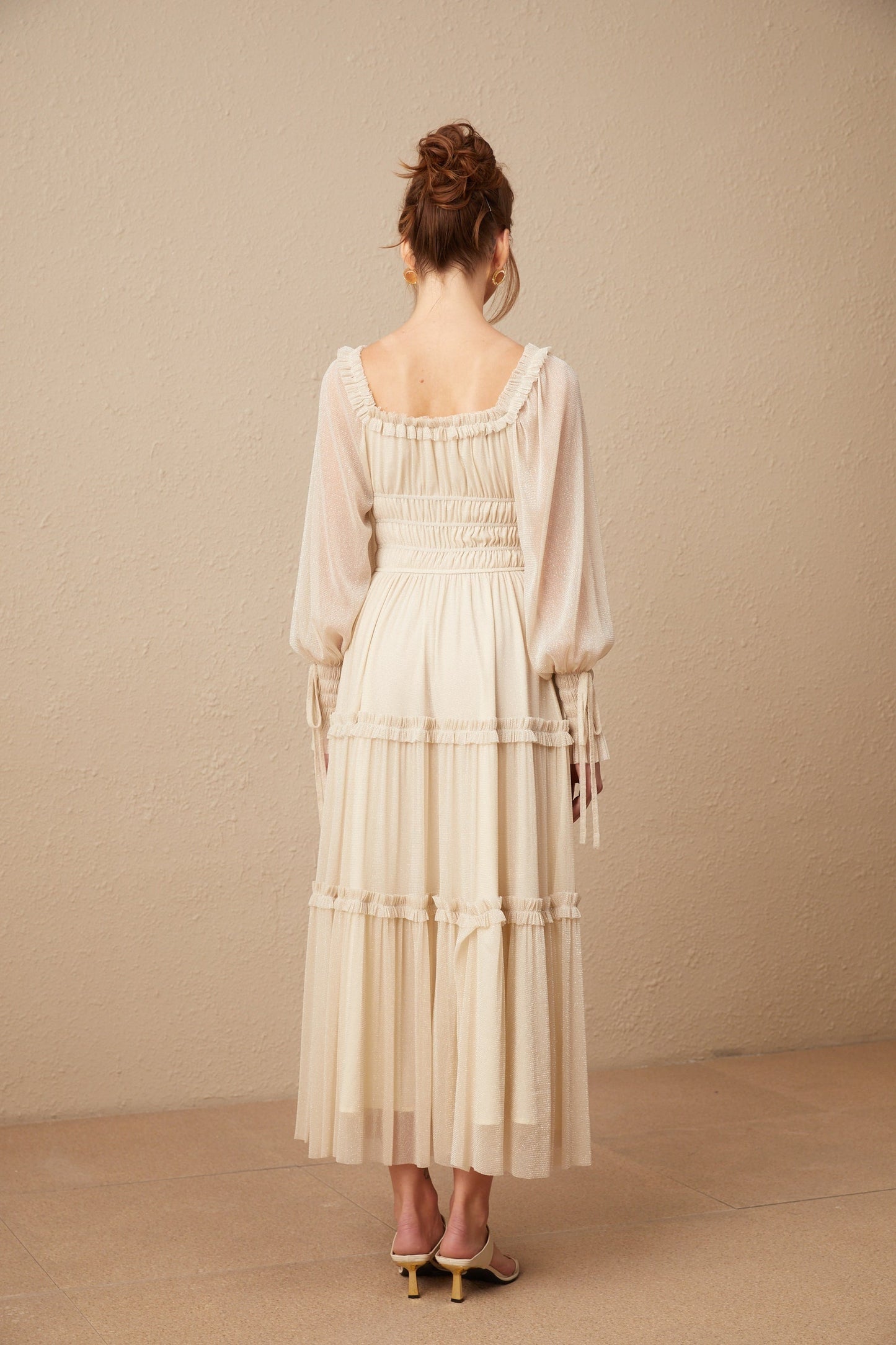 Woman wearing a pleated metallic midi dress with shirred detailing and a flowy silhouette named Camille
