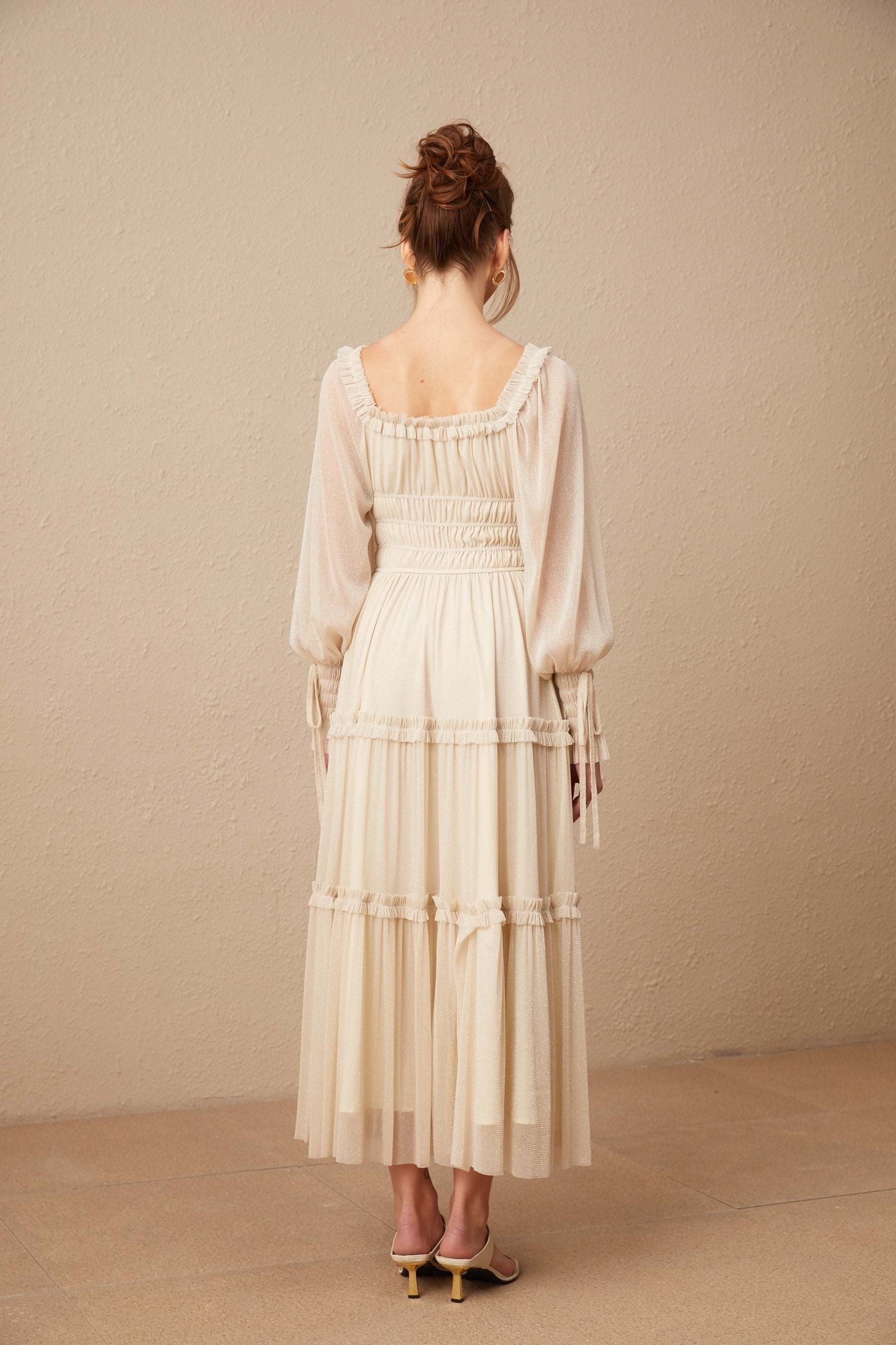 Woman wearing a pleated metallic midi dress with shirred detailing and a flowy silhouette named Camille