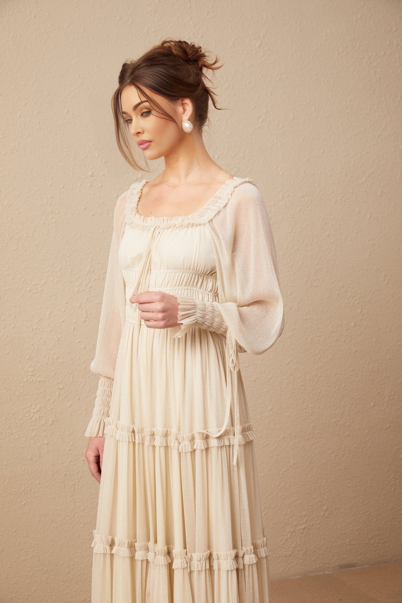 Woman wearing a pleated metallic midi dress with shirred detailing and a flowy silhouette named Camille